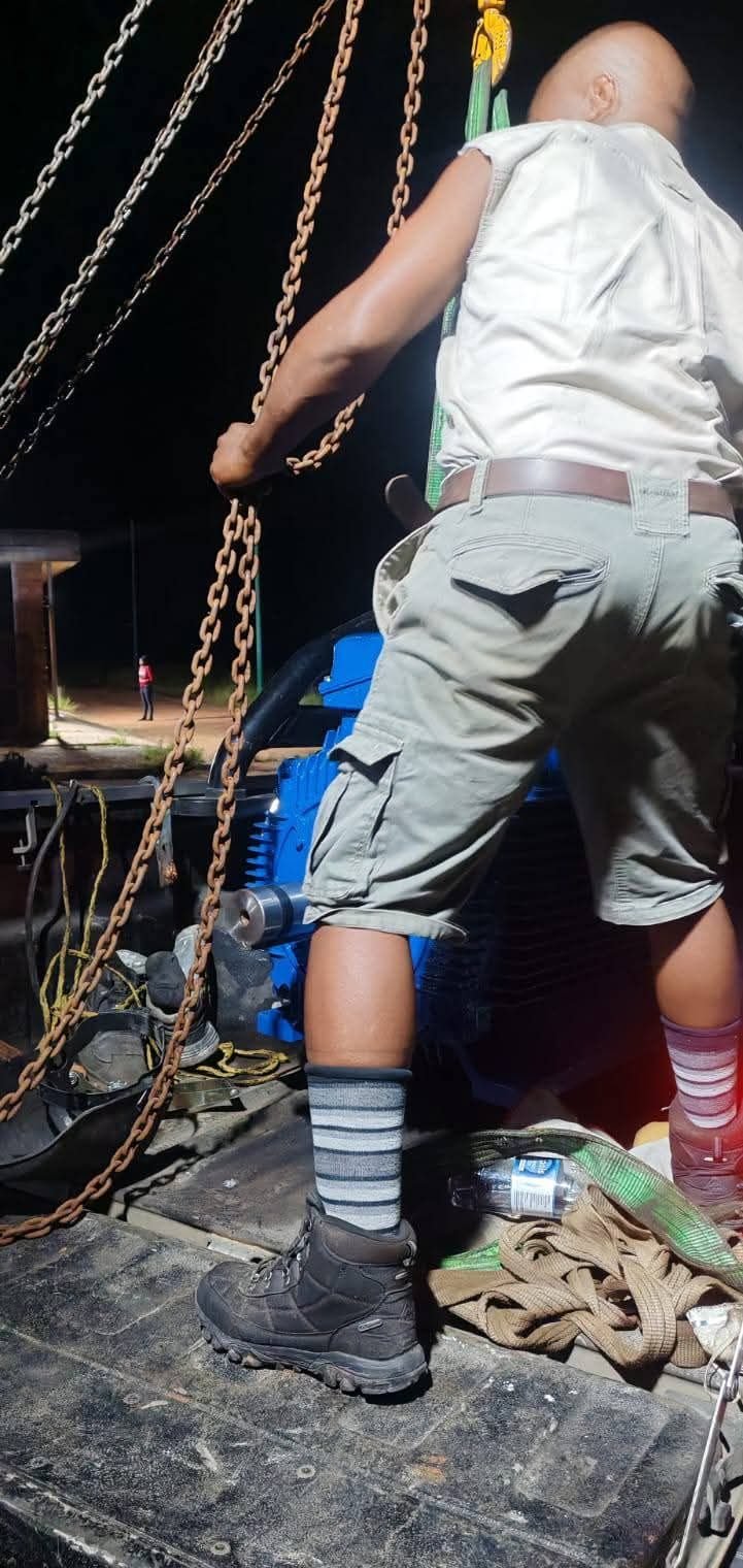 Technician rigging a motor with chains at night
